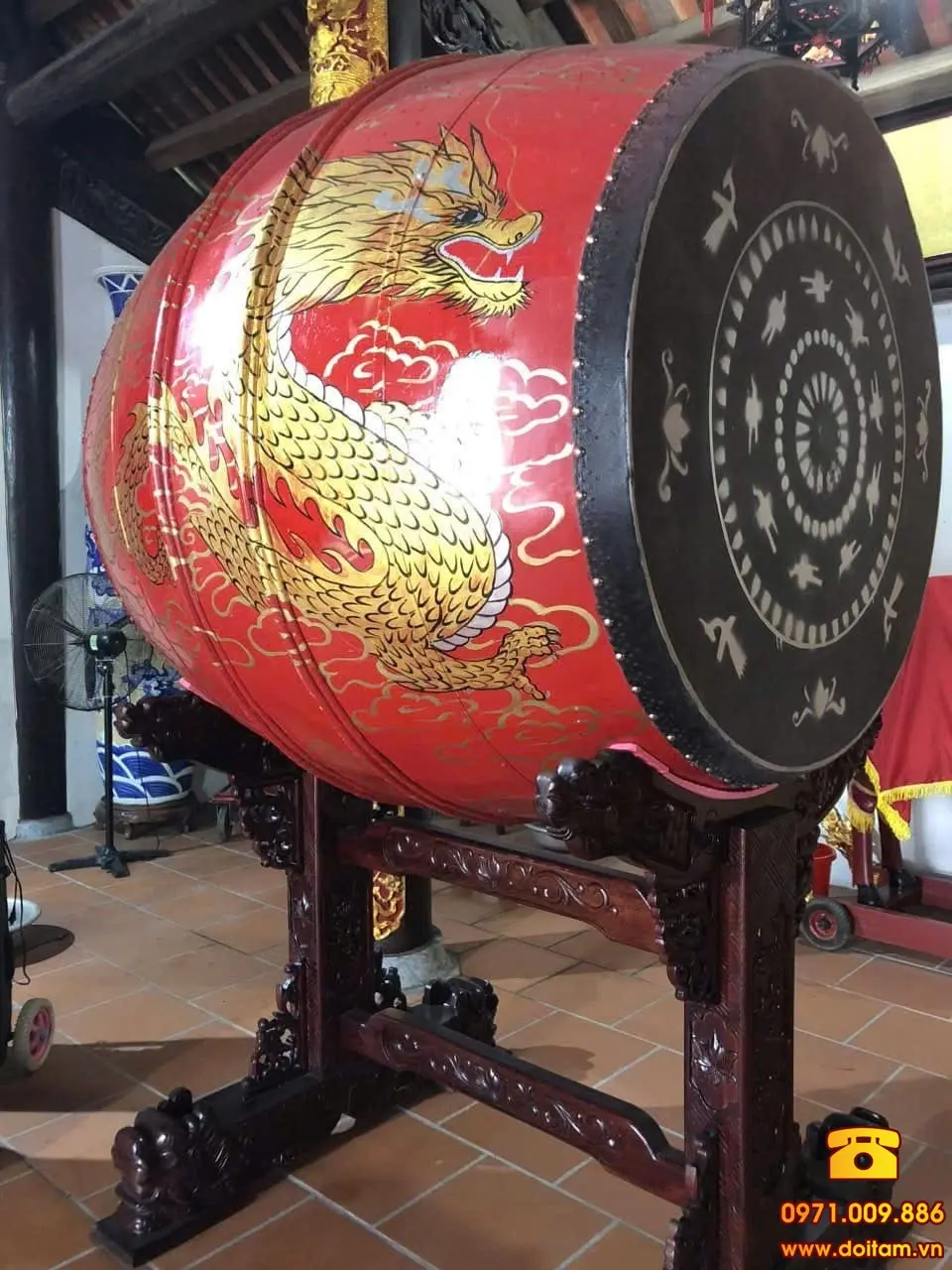 Trống gỗ sơn đỏ nổi bật, thân trống vẽ rồng vàng uy nghi, đặt trên giá gỗ chạm khắc.